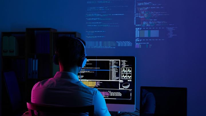 Desarrollador programando en un cuarto con luz azul